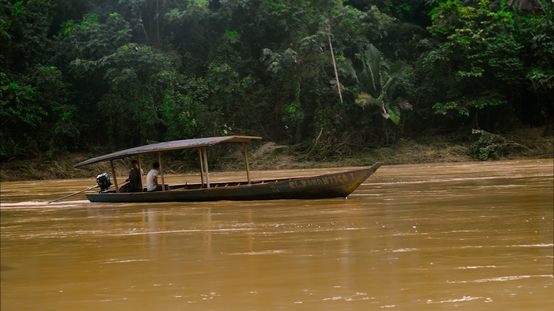 This image shows a boat in a brown river in the jungle.jpg